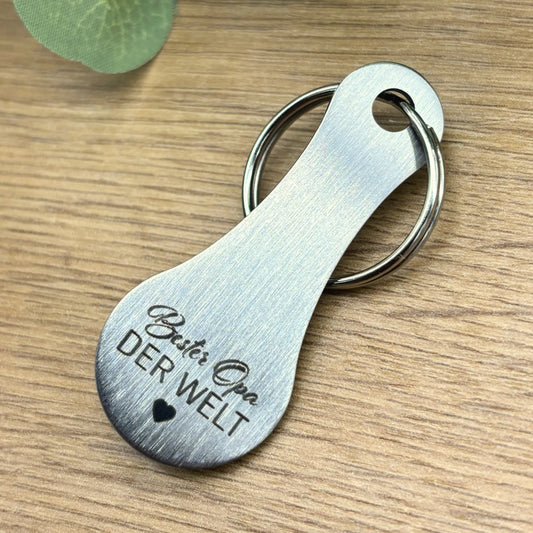 Schlüsselanhänger „Bester Opa der Welt“ aus Edelstahl – hochwertige Gravur, natürlich präsentiert auf Holzuntergrund mit Blattdeko