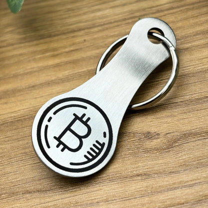 Einkaufswagenchip aus Edelstahl mit hochwertiger Bitcoin-Gravur – robustes Design auf Holzuntergrund.