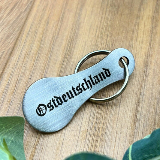 Schlüsselanhänger Einkaufswagenlöser „Ostdeutschland“ aus Edelstahl auf Holztisch