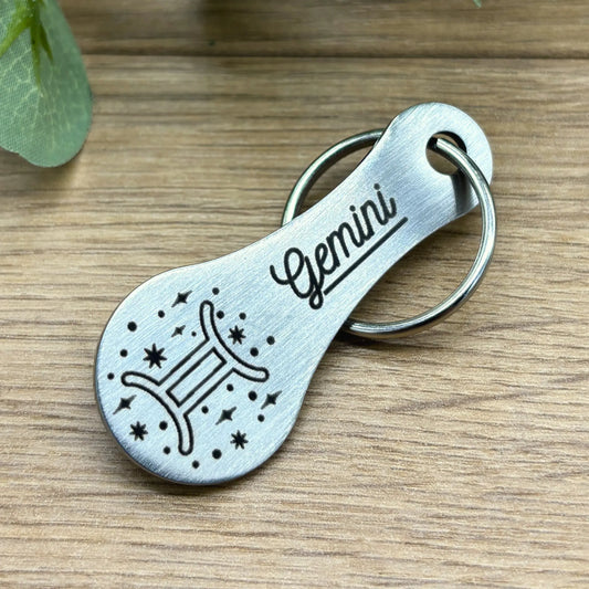 Einkaufswagenlöser mit Gravur Sternzeichen Zwilling – minimalistisches Design aus Edelstahl auf Holzuntergrund